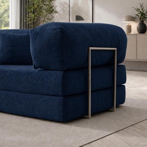 May include: A modular navy blue corduroy sofa with a modern design. The sofa features a stacked construction with a metal frame and a matching navy blue pillow. The corduroy fabric has a ribbed texture.