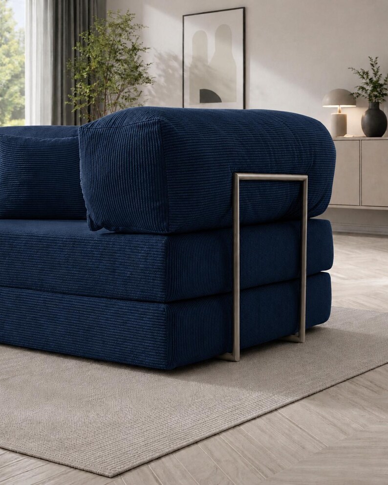 May include: A modular navy blue corduroy sofa with a modern design. The sofa features a stacked construction with a metal frame and a matching navy blue pillow. The corduroy fabric has a ribbed texture.
