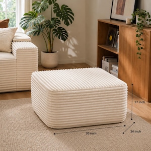 Puede incluir: Otomana de pana color crema, rectangular, con dimensiones de 76 cm de largo, 61 cm de ancho y 43 cm de alto. La otomana est&aacute; colocada sobre una alfombra de tono neutro. Parte de un juego de muebles de sal&oacute;n.