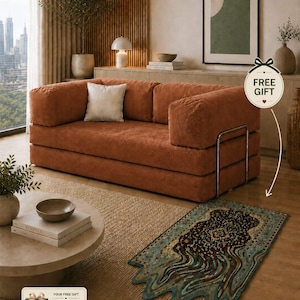 May include: A modern living room setup featuring a rust-colored corduroy sofa with a white pillow. A patterned rug, measuring 23.6 x 35.4 inches, is on the floor. The room includes a round coffee table, artwork, and a free gift promotion.
