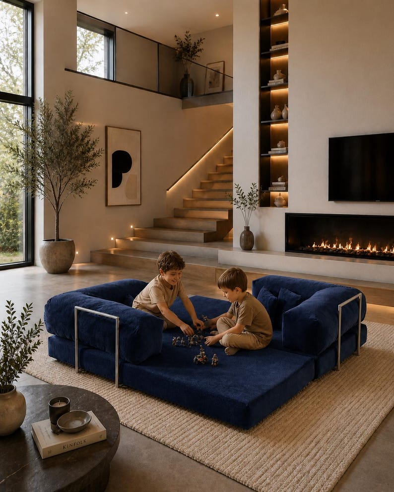 Puede incluir: Un sof&aacute; modular azul marino con detalles met&aacute;licos plateados. Dos ni&ntilde;os juegan en el sof&aacute;. El sof&aacute; est&aacute; sobre una alfombra beige en un sal&oacute;n moderno. La habitaci&oacute;n tiene chimenea, una ventana grande y una escalera.