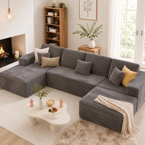 Puede incluir: Un gran sof&aacute; seccional modular de pana gris con m&uacute;ltiples cojines. El sof&aacute; est&aacute; dispuesto en forma de L y se asienta sobre una alfombra de color claro. Cojines decorativos en crema y amarillo a&ntilde;aden color.