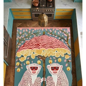 May include: A colorful rug featuring two monkeys under a tree with a pink and yellow umbrella-like canopy. The rug has a teal background and is placed in a kitchen with teal and yellow cabinets and a stainless steel stove.