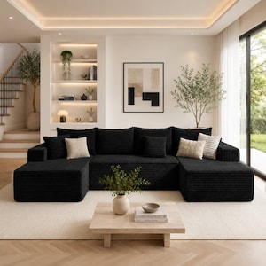 Puede incluir: Sal&oacute;n moderno con un gran sof&aacute; seccional negro con textura de pana y cojines beige y estampados. Una mesa de centro de madera clara con un jarr&oacute;n y libros descansa sobre una alfombra crema. La habitaci&oacute;n tiene una paleta de colores neutros.