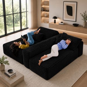 Puede incluir: Sof&aacute; seccional de pana negro de dos piezas con dos personas relaj&aacute;ndose en &eacute;l. Una persona est&aacute; leyendo un libro y la otra est&aacute; durmiendo. El sof&aacute; est&aacute; sobre una alfombra de color claro en un sal&oacute;n moderno.