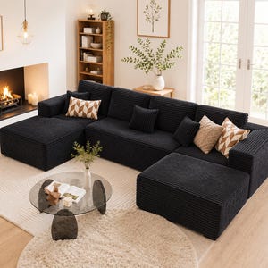 Puede incluir: Un gran sof&aacute; seccional de pana negro con m&uacute;ltiples cojines y una chaise longue. El sof&aacute; est&aacute; colocado sobre una alfombra de color claro, con una mesa de centro de cristal delante. Cojines decorativos en tonos neutros a&ntilde;aden un toque de estilo.