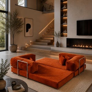 Puede incluir: Un sof&aacute; modular naranja de dise&ntilde;o moderno. El sof&aacute; tiene un perfil bajo y presenta cojines rectangulares y reposabrazos de metal plateado. La habitaci&oacute;n tiene una paleta de colores neutros, una chimenea y una escalera.