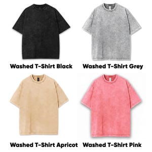 May include: Four short-sleeved, washed t-shirts in black, grey, apricot, and pink. Each shirt has a crew neck and a textured, faded appearance. The text "Washed T-Shirt" is displayed below each shirt, followed by its colour.