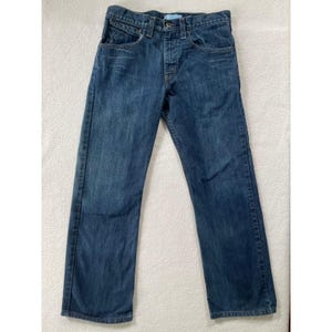 May include: Dark wash denim jeans with a button fly, five-pocket design, and a straight leg. The jeans have a classic, worn look with subtle fading and whiskering details. The jeans are a medium weight and suitable for everyday wear.