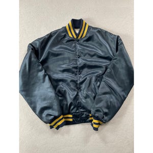 May include: A dark navy blue satin varsity jacket featuring a ribbed collar and cuffs with yellow and navy blue stripes. The jacket has a front button-down closure with matching dark navy blue buttons and long sleeves with a smooth, shiny finish.