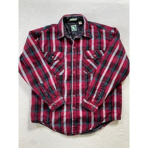 May include: A long-sleeve button-up shirt featuring a plaid pattern in shades of red, black, and white. The shirt includes a pointed collar, two chest pockets with button closures, and a black interior lining with a circular logo on the neck label.