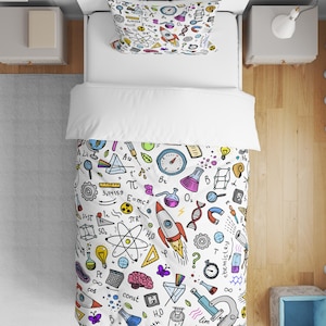 Puede incluir: Juego de funda nórdica y funda de almohada blancas con un colorido estampado de temática científica. El diseño incluye cohetes, vasos de precipitados, fórmulas y símbolos matemáticos. El juego de cama está sobre una cama blanca.