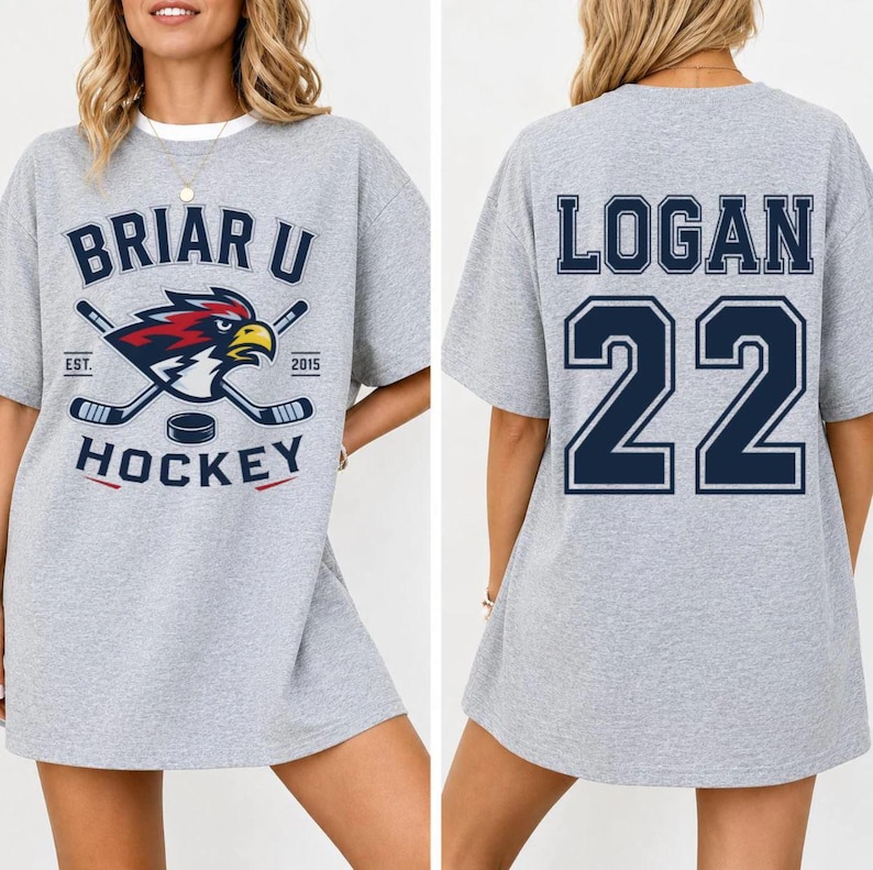 Puede incluir: Camiseta gris oversize con cuello blanco. La parte delantera presenta un logotipo de Briar U Hockey con palos de hockey cruzados, un disco y un &aacute;guila estilizada. La parte trasera muestra "LOGAN" y el n&uacute;mero "22" en azul marino.