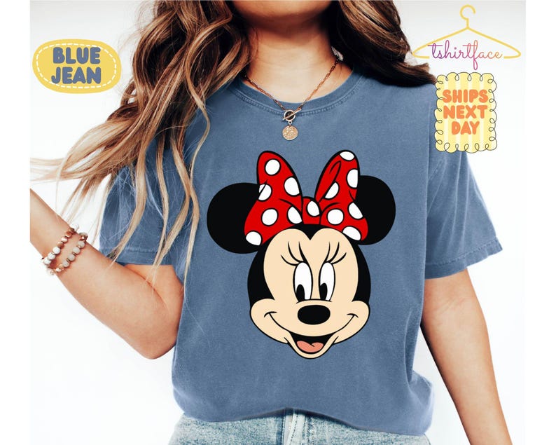 May include: Blue t-shirt featuring a Minnie Mouse graphic. The graphic shows Minnie's face with a red bow with white polka dots. The shirt has the text "BLUE JEAN" and "tshirtface SHIPS NEXT DAY".