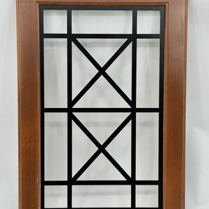 May include: A rectangular wooden cabinet door with a dark brown frame and a black metal grid design. The grid features horizontal and vertical lines, with two intersecting diagonal lines in the centre.