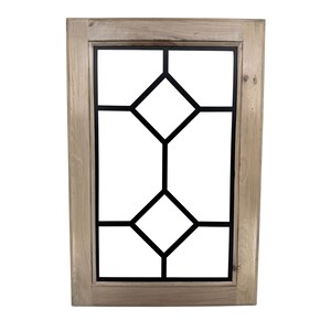 May include: A rectangular wooden frame with a black geometric design. The frame is made of light-colored wood, and the interior features a symmetrical pattern of black lines forming diamond shapes. The design is centered within the frame.