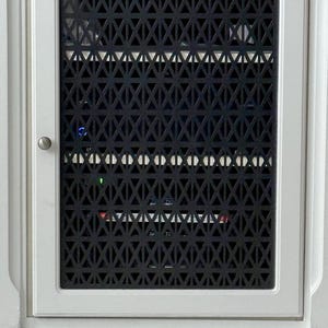 May include: A white cabinet door featuring a black geometric patterned insert. The insert is made up of triangles and diamond shapes. A small silver knob is on the left side of the door.