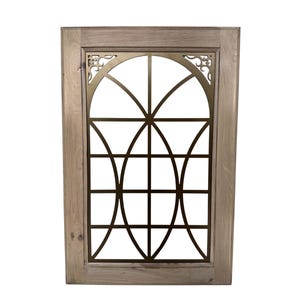 Puede incluir: Un marco de madera rectangular con una inserción metálica decorativa. La inserción presenta un diseño geométrico con arcos y líneas que se cruzan en color bronce. El marco de madera tiene un acabado claro y natural.