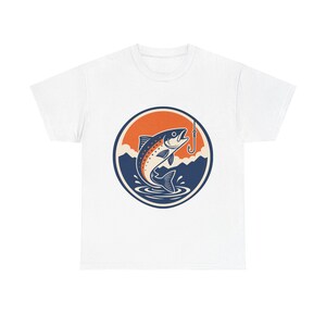May include: White t-shirt featuring a circular graphic of a jumping fish with a fishing hook. The design includes an orange and blue color scheme with mountain and water details. A classic tee for fishing enthusiasts.
