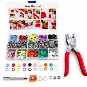 May include: A clear plastic organiser box filled with colourful snap fasteners and a red-handled metal snap setter tool. The box contains various colours of snaps, including blue, pink, yellow, green, and black. The box also includes a user manual.