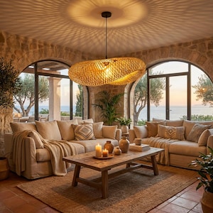 Könnte beinhalten: Wohnzimmer mit einer großen, gewebten Pendelleuchte aus Rattan. Der Raum verfügt über beige Sofas, einen Holztisch und einen Jute-Teppich. Große Bogenfenster bieten einen Blick auf das Meer und die Bäume.