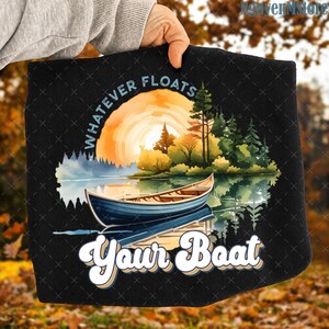 Könnte beinhalten: Schwarzes T-Shirt mit einem See-Motiv, Boot, Bäumen und Sonnenuntergang. Der Text "WHATEVER FLOATS" steht über der Szene, darunter "YOUR BOAT" in einer stilisierten Schriftart.