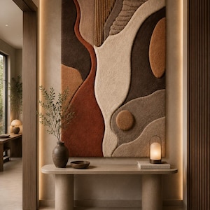 May include: A large rectangular wall hanging featuring a textured, tufted surface with abstract organic shapes in shades of terracotta, cream, dark brown, and tan. The piece displays varied pile heights and linear patterns, creating a tactile, layered appearance that covers the wall space above a console table.