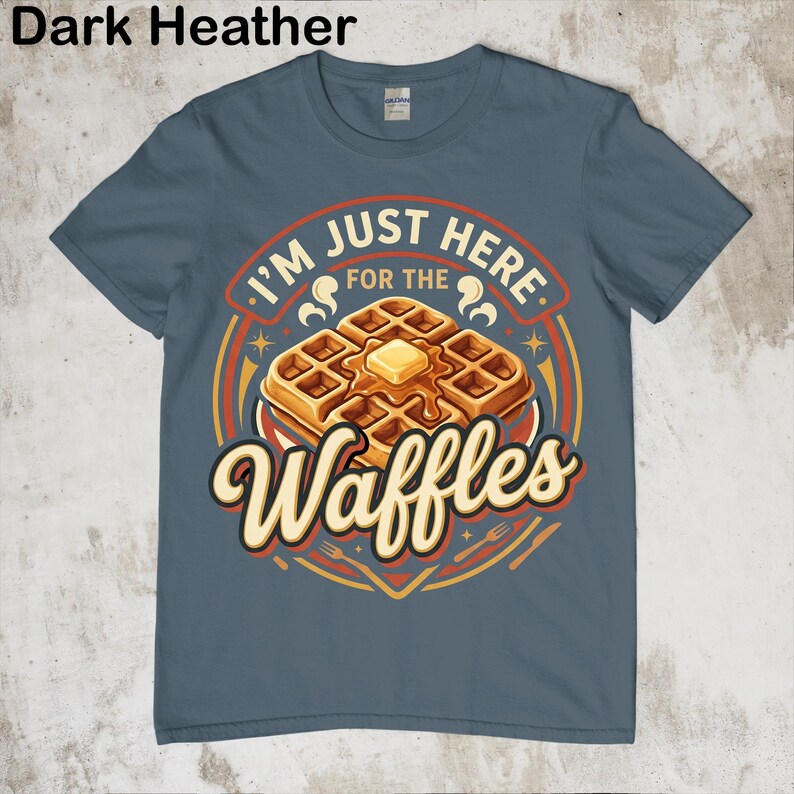 Puede incluir: Camiseta azul oscuro jaspeado con un gr&aacute;fico de gofres. El gr&aacute;fico dice "I'm just here for the Waffles" en un dise&ntilde;o circular con una ilustraci&oacute;n de gofre y mantequilla. La camiseta es de cuello redondo y manga corta.