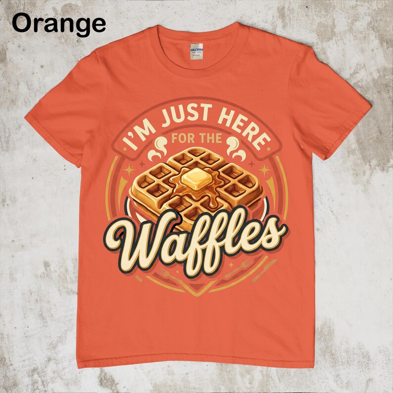 Puede incluir: Camiseta naranja con un gr&aacute;fico de gofres. El gr&aacute;fico presenta una pila de gofres con mantequilla y el texto "I'M JUST HERE FOR THE Waffles". La camiseta es de color naranja liso.