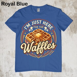 Puede incluir: Camiseta azul real con un gr&aacute;fico de gofres. El dise&ntilde;o presenta una pila de gofres con mantequilla y el texto "I'M JUST HERE FOR THE Waffles". El dise&ntilde;o incluye colores naranja, amarillo y marr&oacute;n.