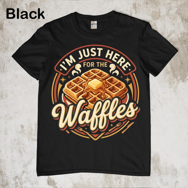 Puede incluir: Camiseta negra con un gr&aacute;fico de gofres. El dise&ntilde;o presenta una pila de gofres con mantequilla y el texto "I'm just here for the Waffles". El dise&ntilde;o es en tonos marrones, amarillos y rojos.