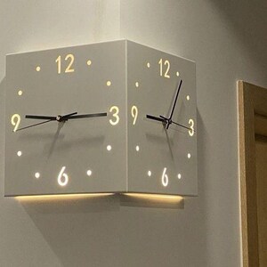 May include: A handmade wooden sign with the text "Welcome to our home" in a handwritten style. The sign is painted white with a dark stained wooden frame. A small green plant is placed on the sign.