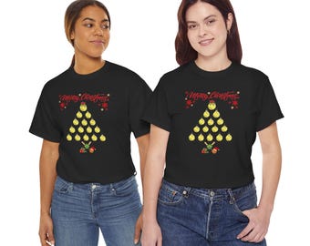 May include: A black short-sleeve t-shirt featuring a graphic of a Christmas tree made from yellow softball ornaments. The text Merry Christmas is printed in red above the tree, with small red stars and softball-themed gifts at the base.