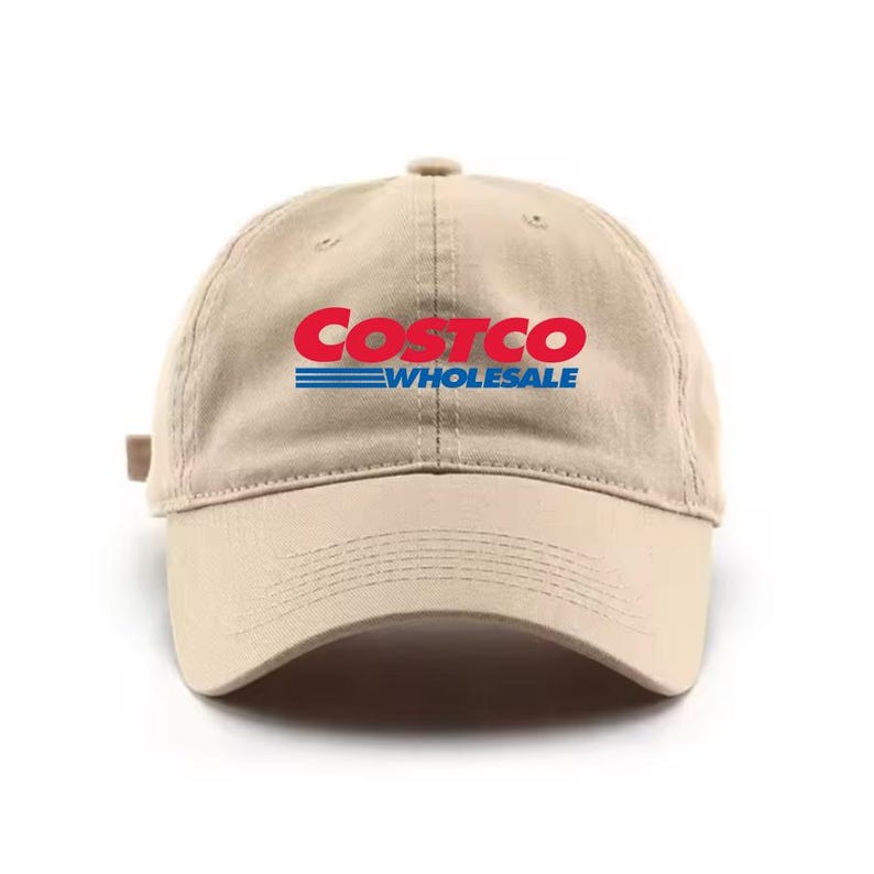 May include: A tan baseball cap with the Costco Wholesale logo in red and blue. The hat has a curved brim and an adjustable strap at the back. The logo is centered on the front of the cap.