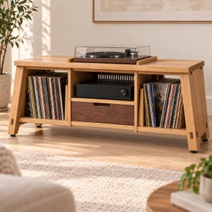 May include: A light oak media console featuring a central drawer with a dark wood front, two open side compartments filled with vinyl records, and a top surface holding a black turntable with a clear dust cover and a black amplifier.