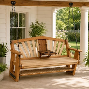 May include: A wooden porch swing with a natural finish, featuring a slatted backrest and a fold-down center console with two integrated cup holders. The bench is suspended by black metal chains attached to a sturdy overhead wooden beam.
