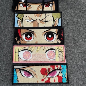 May include: Embroidered patches featuring anime eyes with various expressions. The patches showcase detailed stitching and vibrant colors, including red, pink, and blue. Each patch is rectangular with a black border, suitable for clothing or accessories.