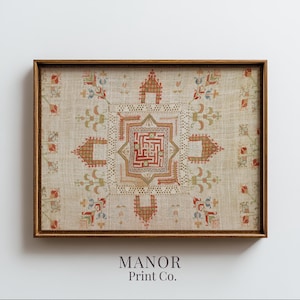 May include: A rectangular framed wall art piece featuring a beige linen-textured background with intricate, symmetrical embroidery in shades of red, green, and blue. The central design is a geometric maze pattern surrounded by stylised floral motifs.