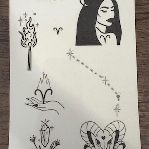 May include: A sheet of temporary tattoos featuring Aries-themed designs. Includes a woman with ram horns, a ram skull, a constellation, a hand holding a flame, a match with a flame, a crystal, and the word "Aries".