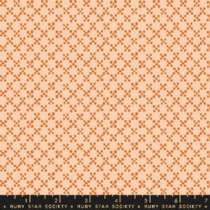 May include: Peach-coloured fabric featuring a repeating pattern of rust-coloured cross-shaped designs. The fabric has a subtle texture and a consistent pattern across the surface. The bottom of the image shows a ruler with the text "RUBY STAR SOCIETY".