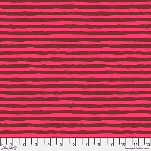 May include: Red and brown striped fabric with a repeating pattern. The fabric is shown with a ruler for scale.