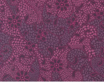 May include: Close-up of a fabric with a floral pattern in shades of purple and pink. The design features stylized flowers and swirling shapes, created with small, dotted textures. The fabric has a textured appearance and a dark purple background.