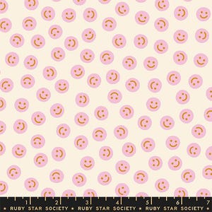 May include: A cream-colored fabric with a repeating pattern of pink smiley faces with orange smiles. The fabric is from Ruby Star Society.