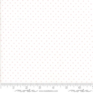 May include: White fabric with a repeating pattern of small pink dots. The fabric is measured with a ruler that has the word "moda" printed on it.