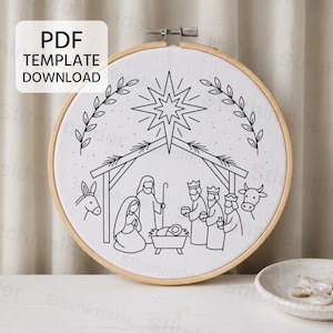 Può includere: Un telaio da ricamo circolare in legno contenente tessuto bianco con un motivo a linee nere di una scena della natività, inclusi una stella, una stalla, figure e animali. Un riquadro bianco in alto a sinistra mostra il testo PDF TEMPLATE DOWNLOAD.