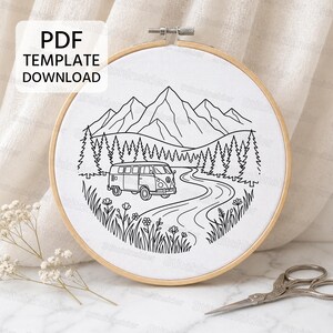 May include: A circular wooden embroidery hoop containing white fabric with a black line art design of a camper van on a winding road, surrounded by pine trees, mountains, and wildflowers. The text PDF TEMPLATE DOWNLOAD is visible.