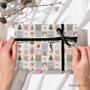 以下が含まれることがあります： クリスマスツリー、リボン、葉のイラストが描かれたパステルカラーの正方形のグリッド模様の包装紙で包まれた長方形のギフトボックス。パッケージの中央には、ダークグリーンのベルベットのリボンが水平に結ばれています。