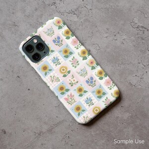 Op de afbeelding: Een witte telefoonhoes met een bloemenpatroon met zonnebloemen, blauwe bloemen en roze rozen. Het ontwerp is gerangschikt in een patchworkstijl met lichtblauwe en roze vierkanten. De tekst "Sample Use" is zichtbaar.
