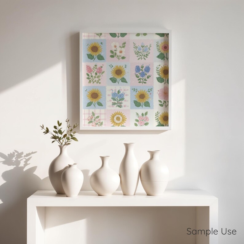 Op de afbeelding: Een wit omkaderde bloemenprint met zonnebloemen en andere bloemen in een rasterpatroon hangt boven een witte plank. Vijf witte keramische vazen ​​van verschillende vormen zijn op de plank geplaatst.