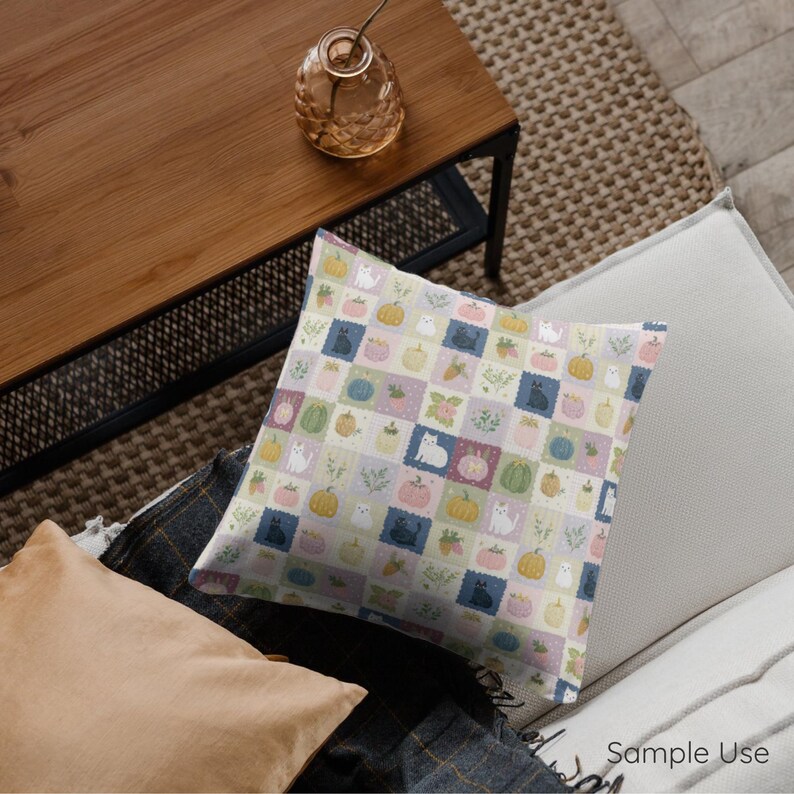 May include: A square throw pillow featuring a grid pattern of pastel-colored squares. Each square contains illustrations of cats, pumpkins, and sprigs of greenery in shades of pink, yellow, green, blue, and white against a light background.